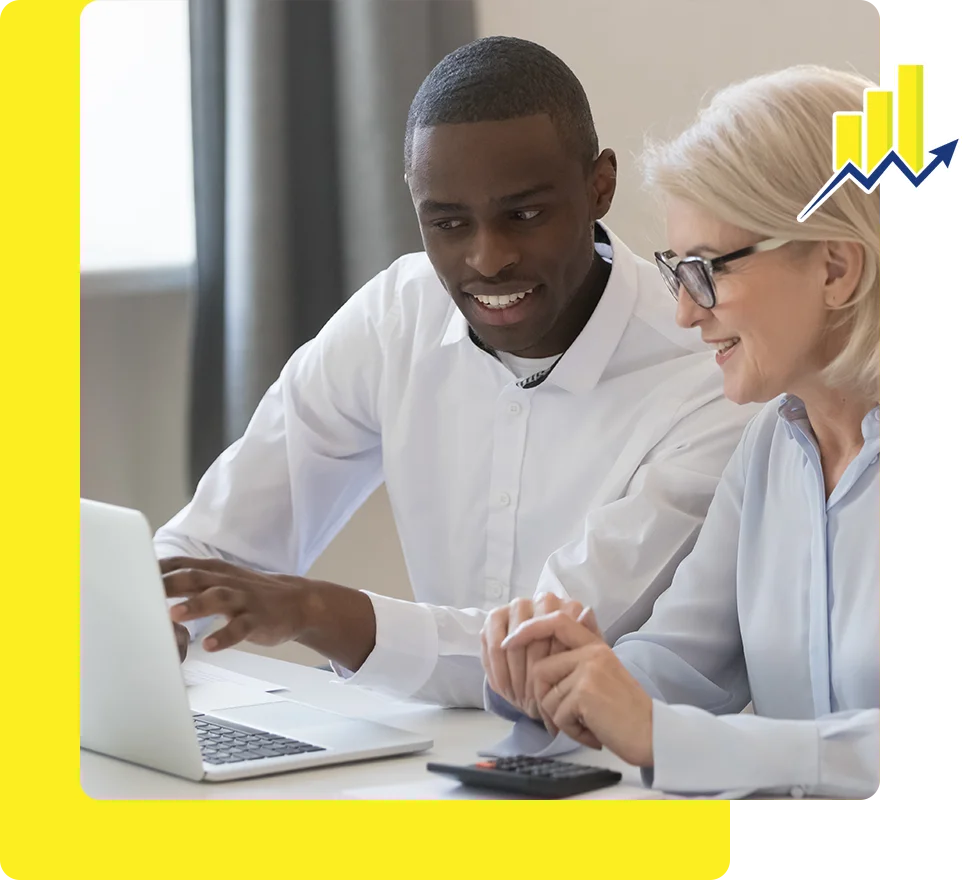 Two people sitting at a table looking at a laptop.