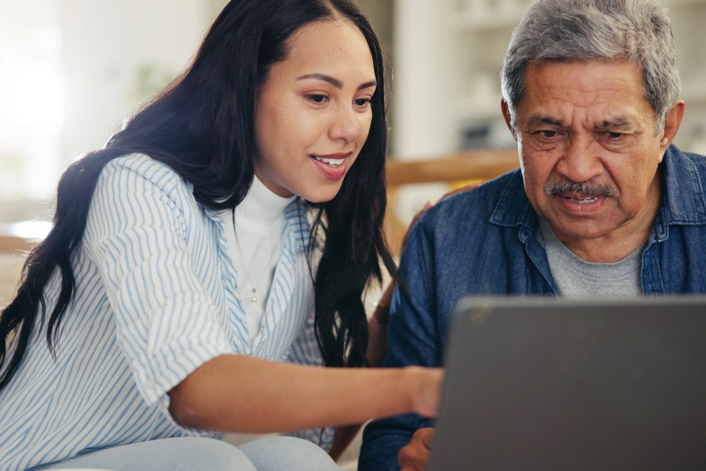 A woman and an older man looking at a laptop.