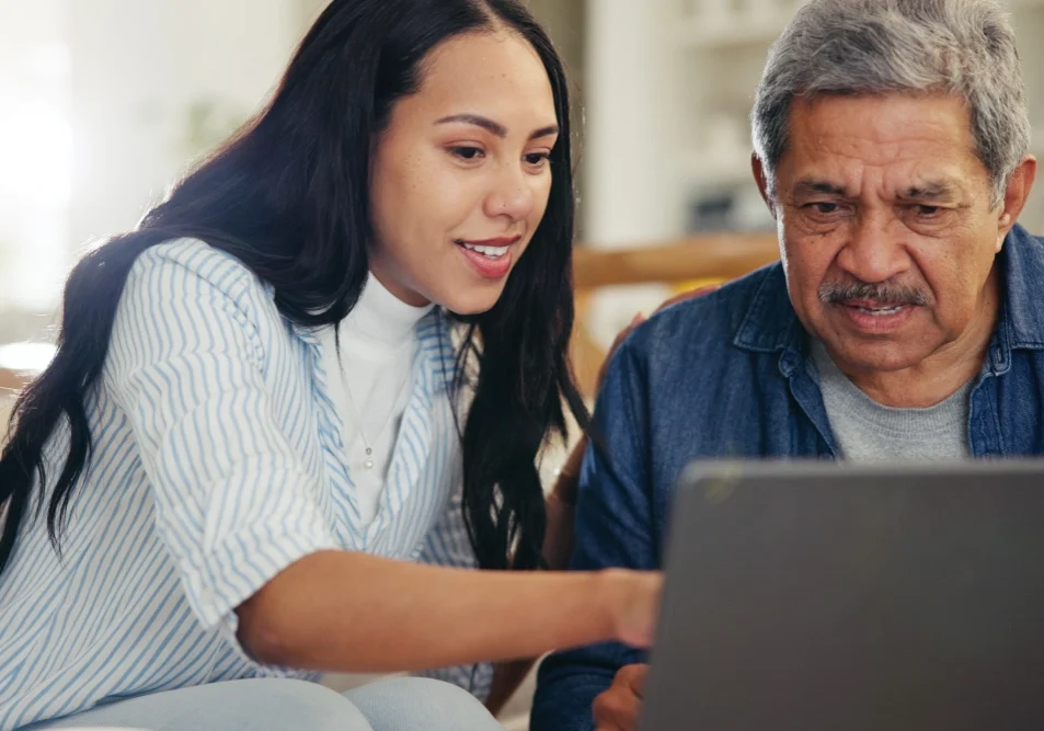 A woman and an older man looking at a laptop.